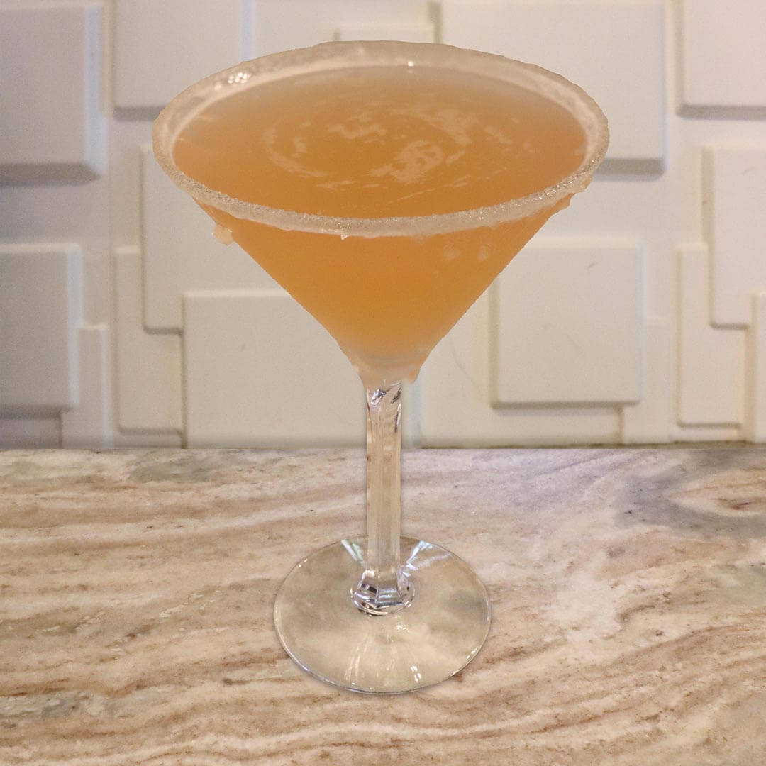 A vibrant, soft orange-pink grapefruit cocktail served in a chilled glass.
