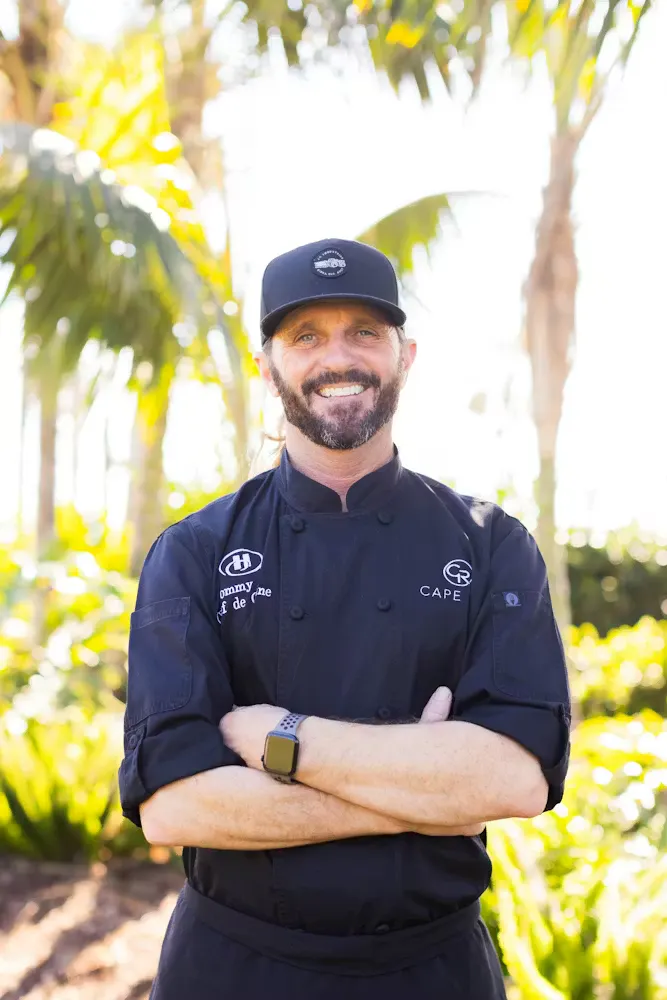 a chef standing next to a palm tree
