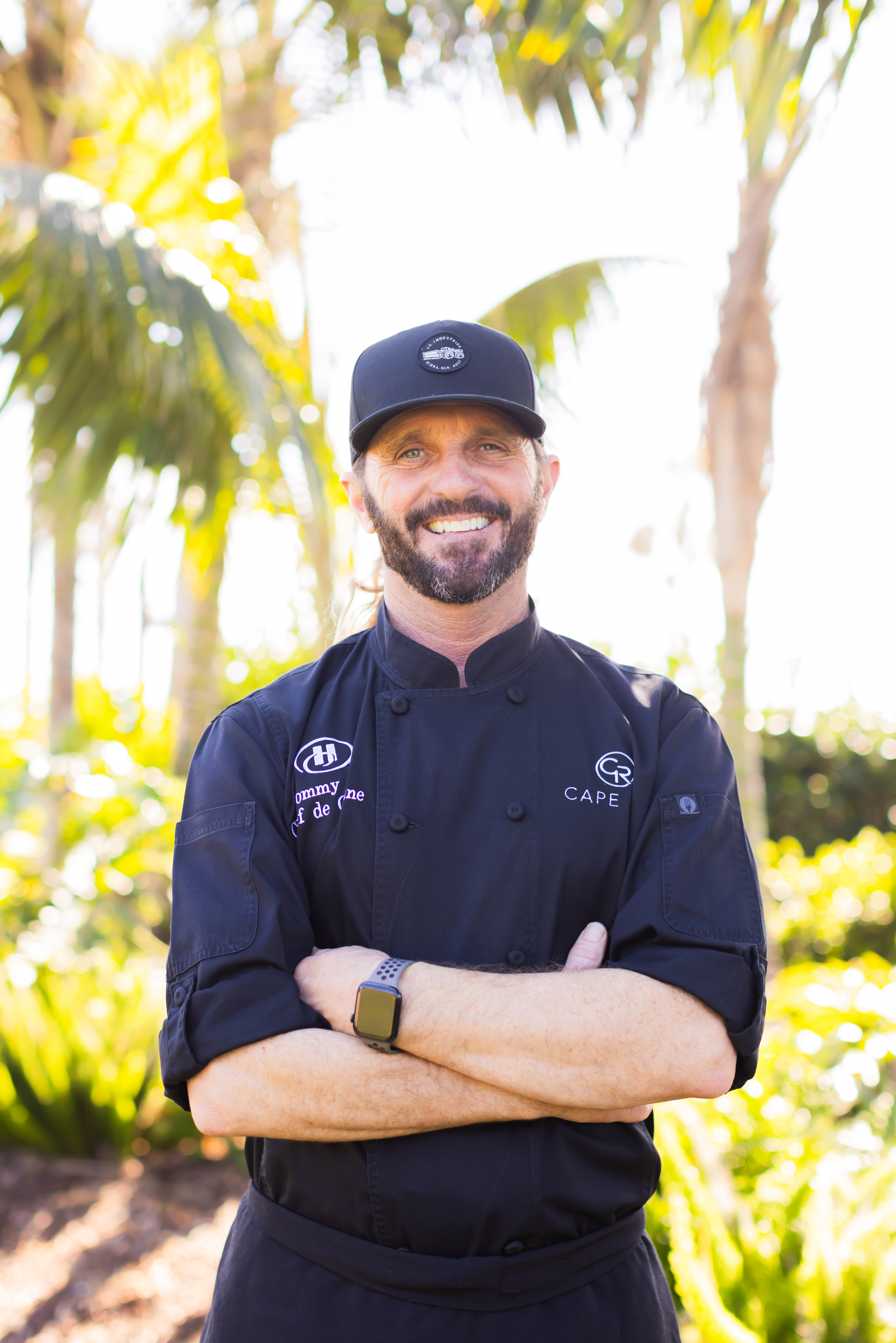 a chef standing next to a palm tree