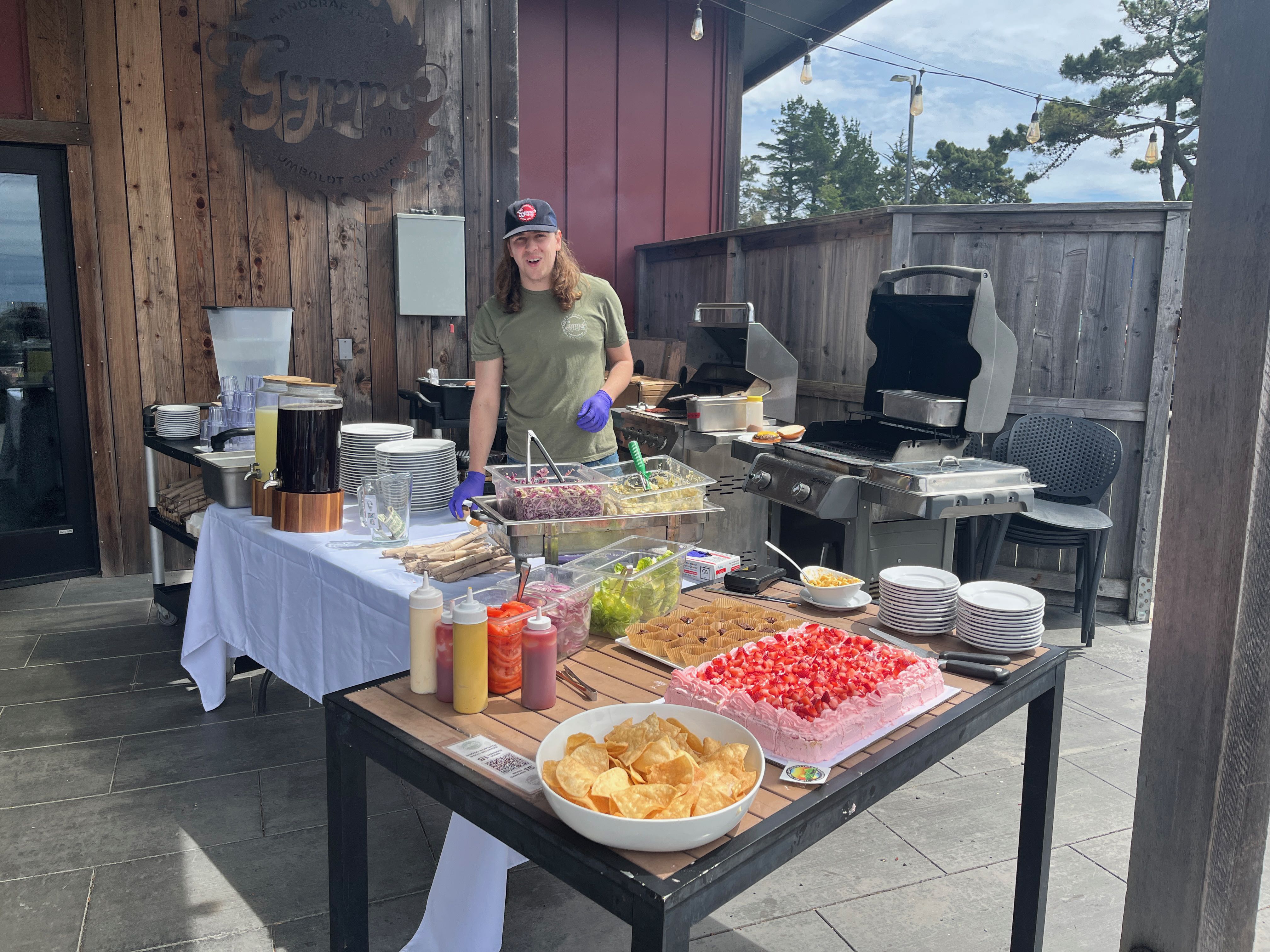 a woman standing behind a table with food on it