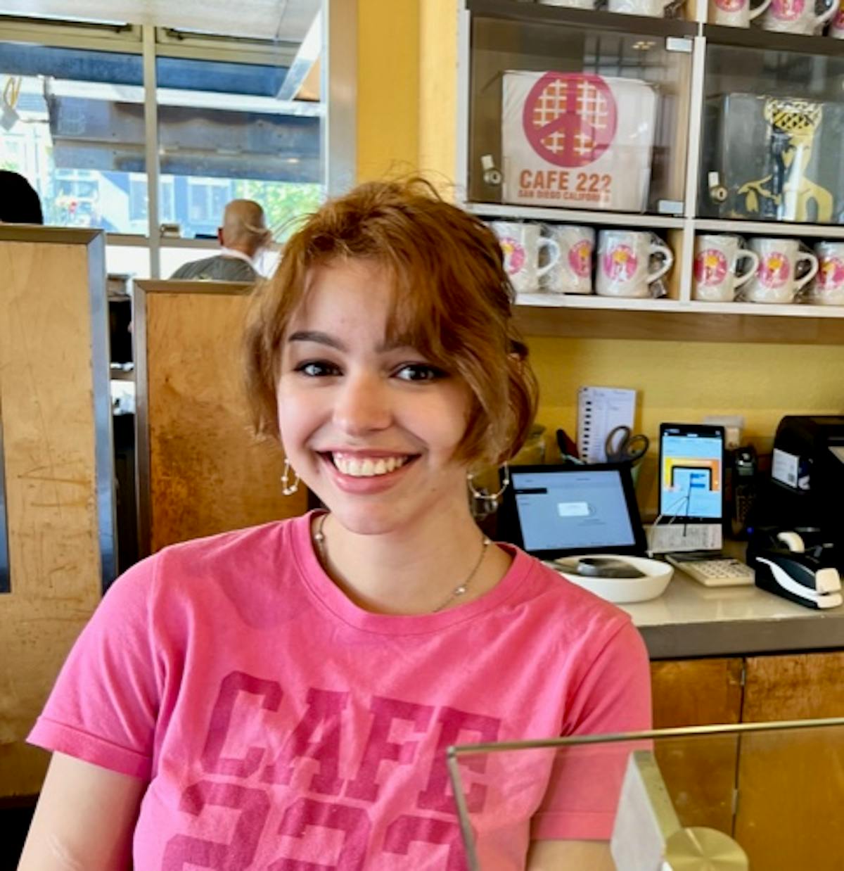 a girl sitting at a table and smiling at the camera