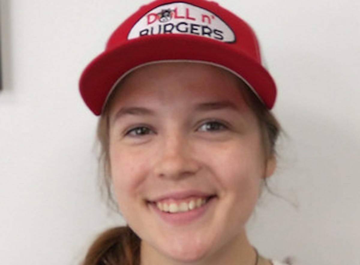 a young girl wearing a hat and smiling at the camera