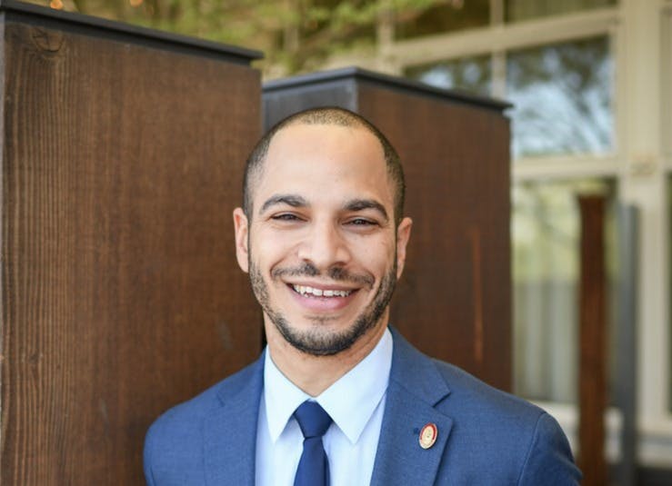 a man wearing a suit and tie smiling at the camera