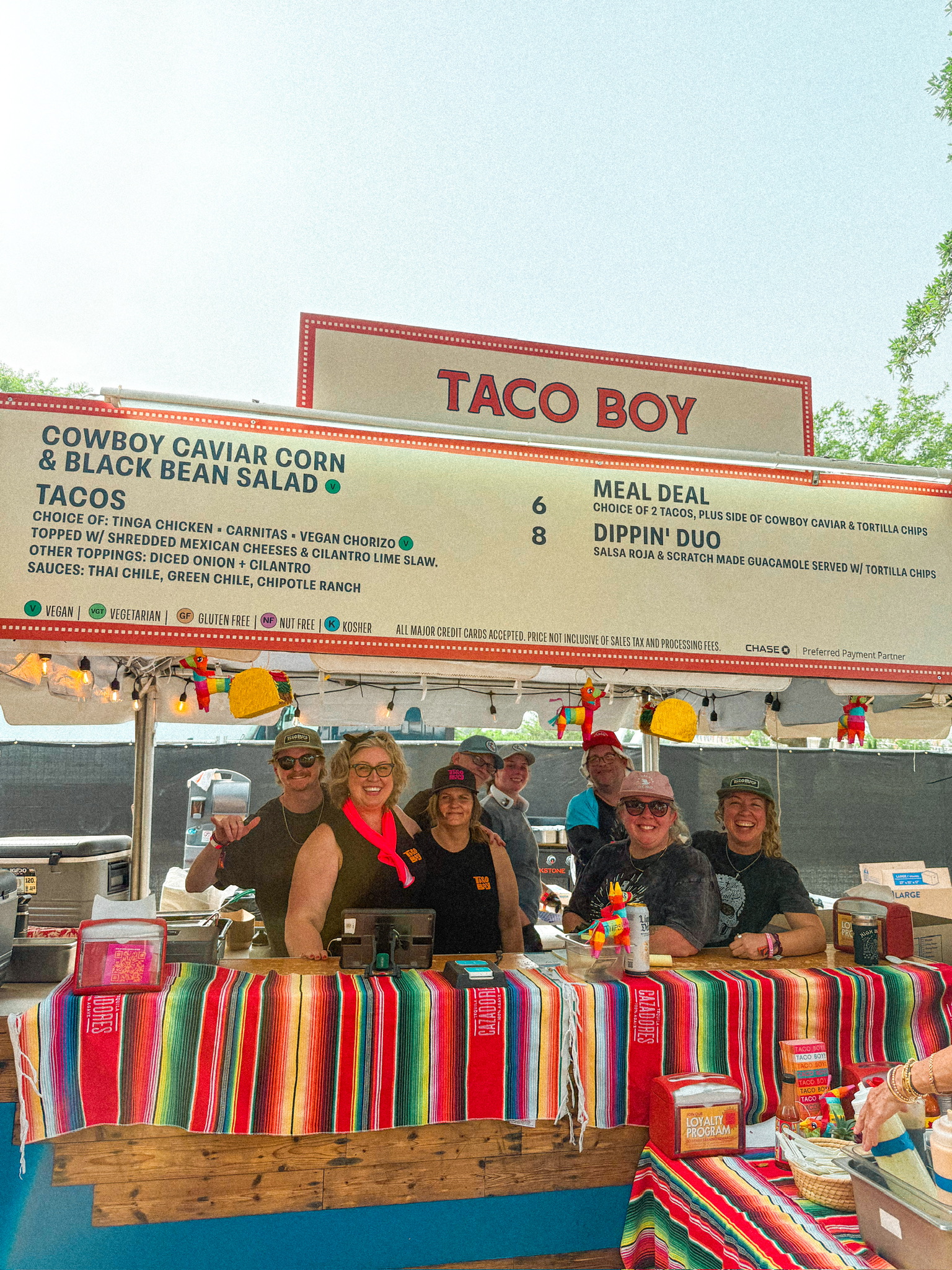 a group of people standing behind a table with food