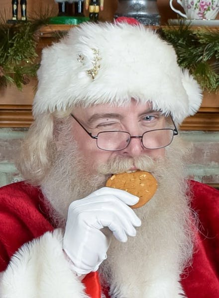 a man wearing glasses eating a hot dog
