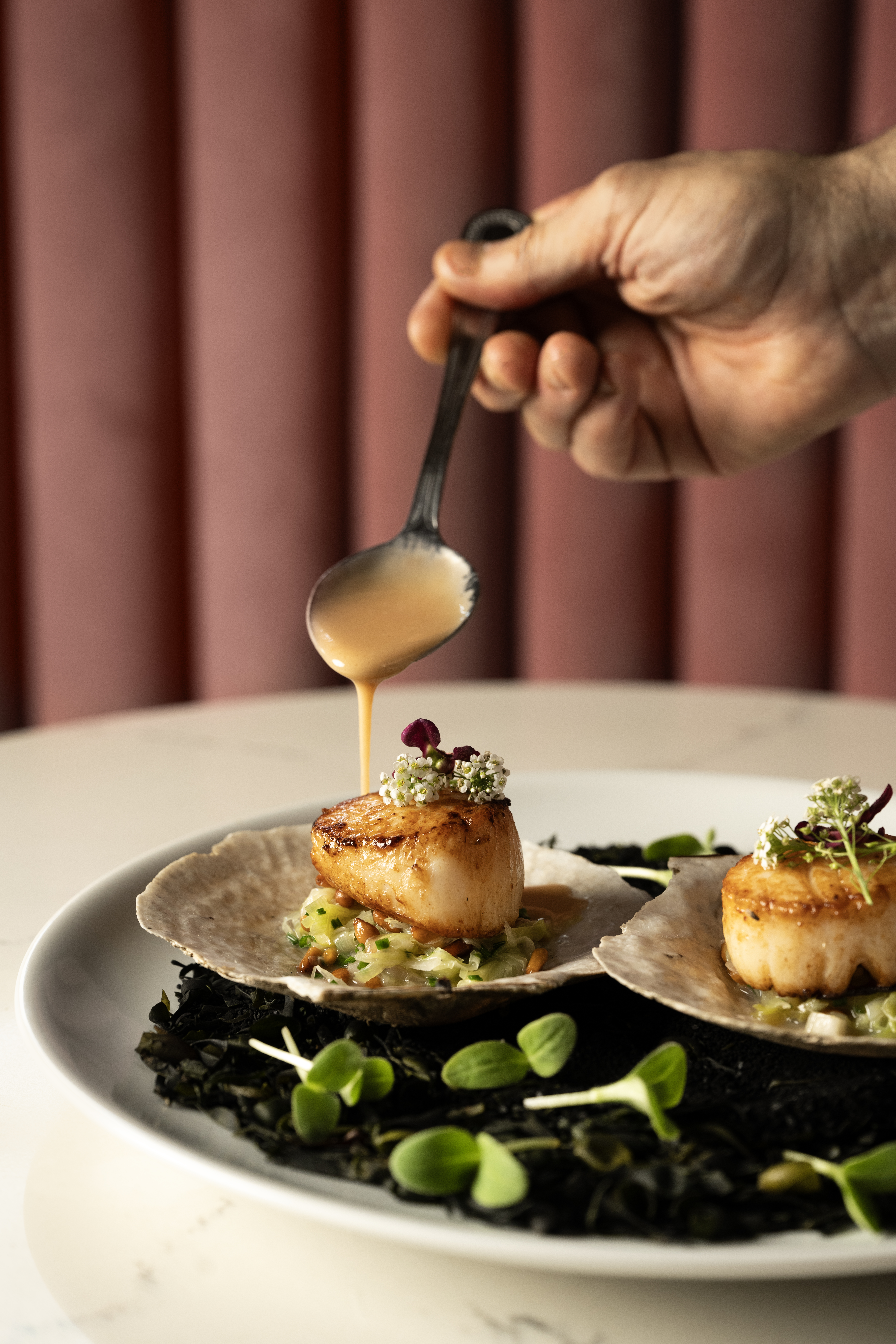a person holding a plate of food on a table