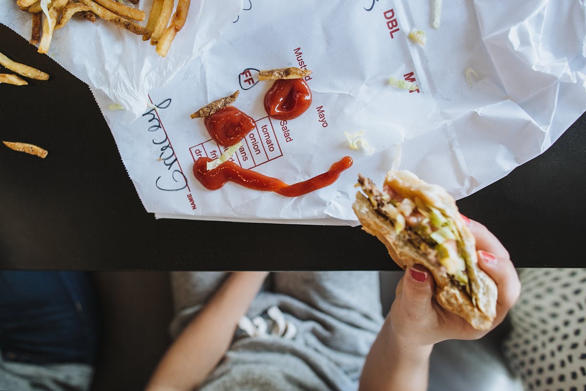 a person holding a hot dog on a bed