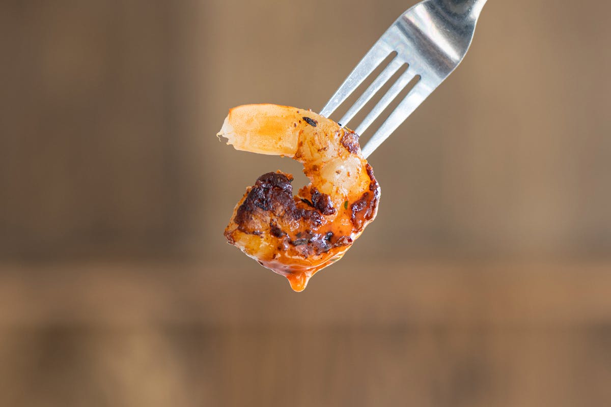 a close up of a shrimp hold by a fork