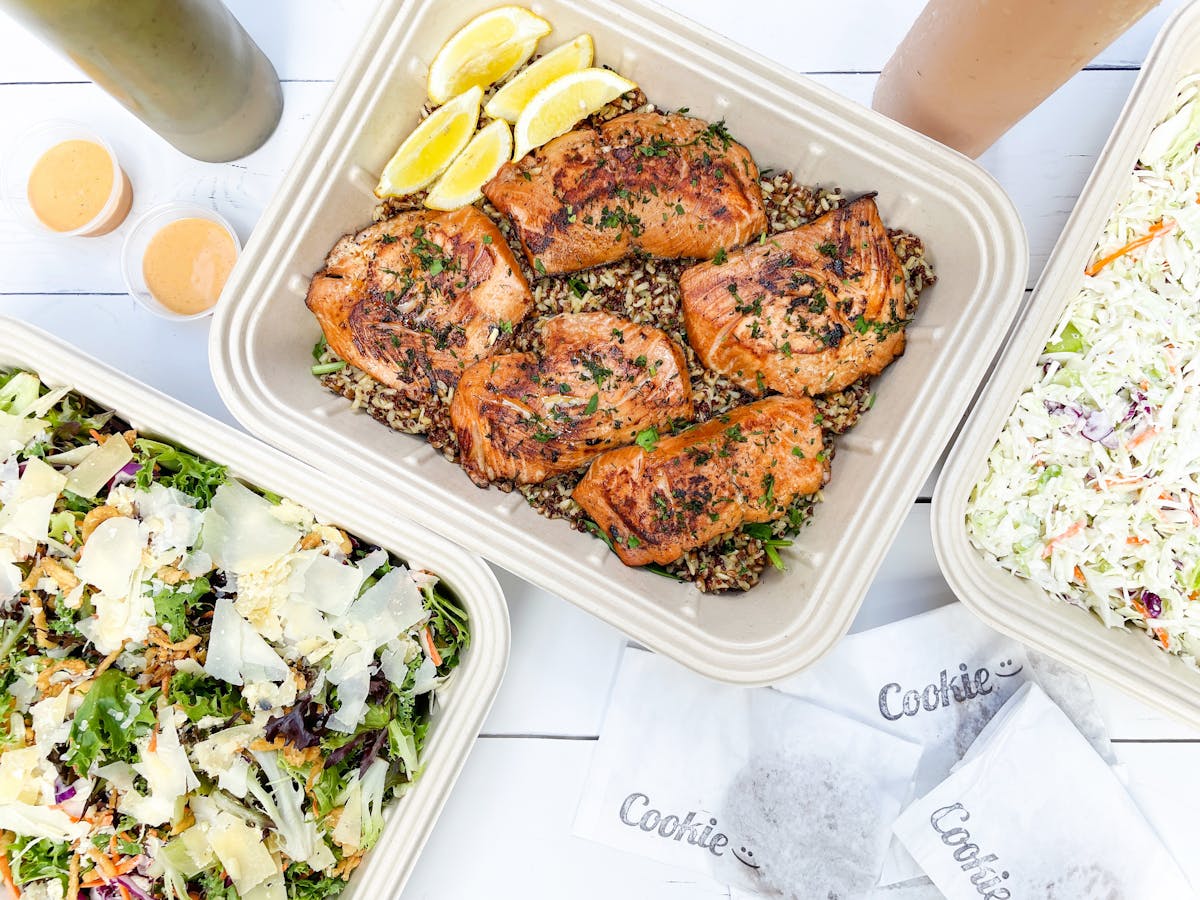 a close up of a plate of food with salads and grilled salmon