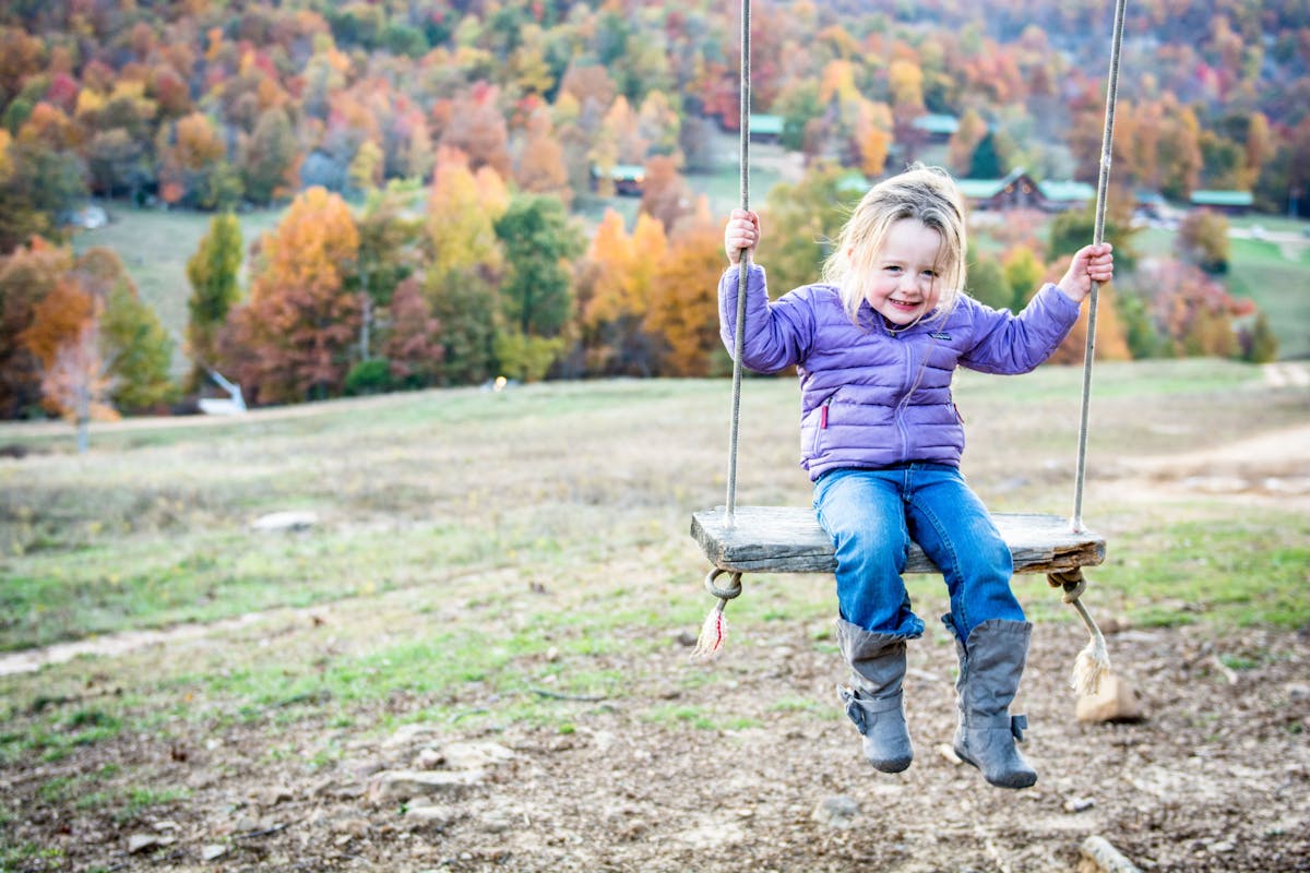 a little boy holding a kite in a swing