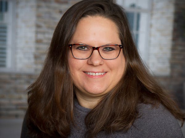 a woman wearing glasses and smiling at the camera