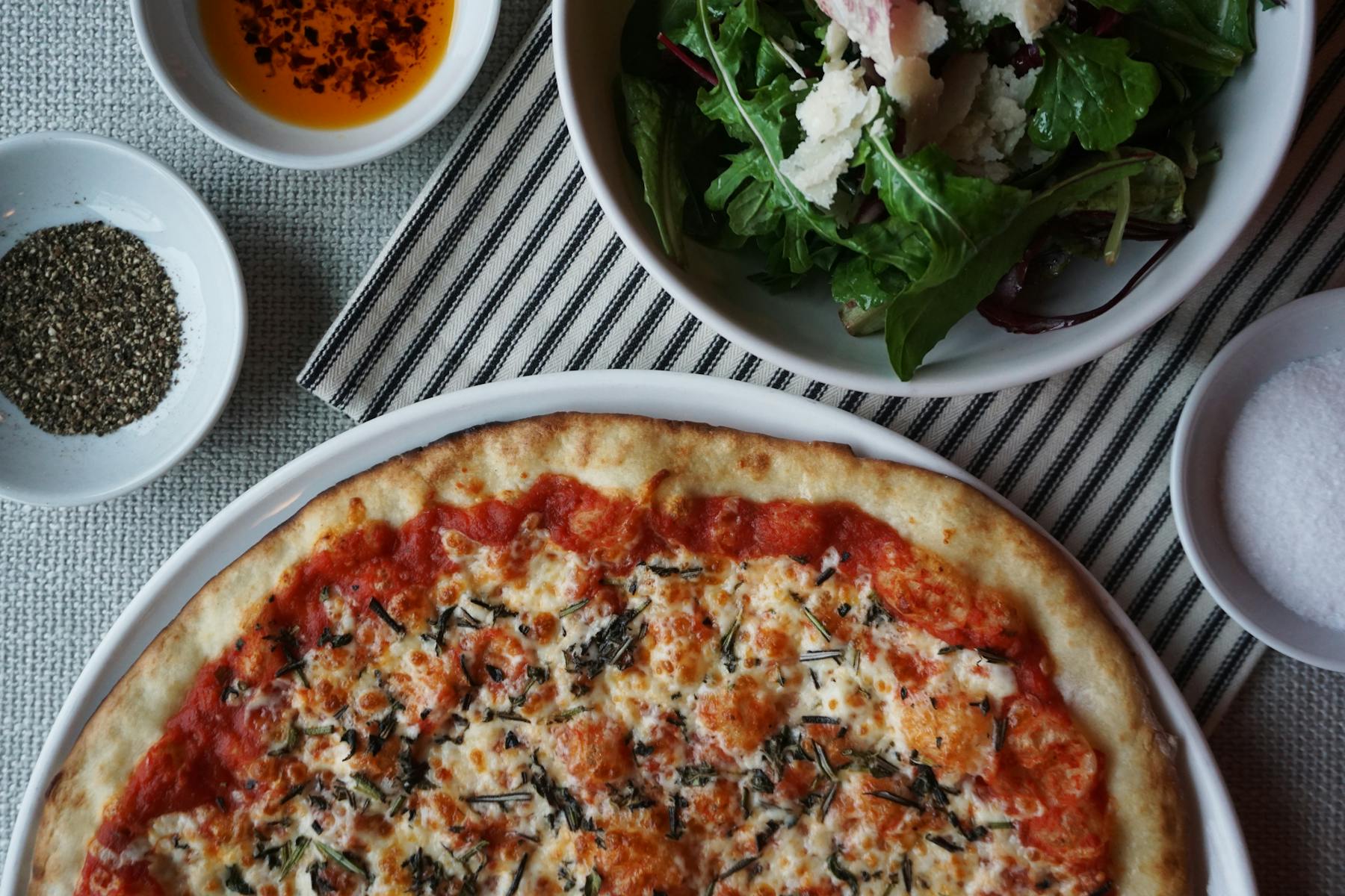 a meal of pizza and a bowl of food on a plate