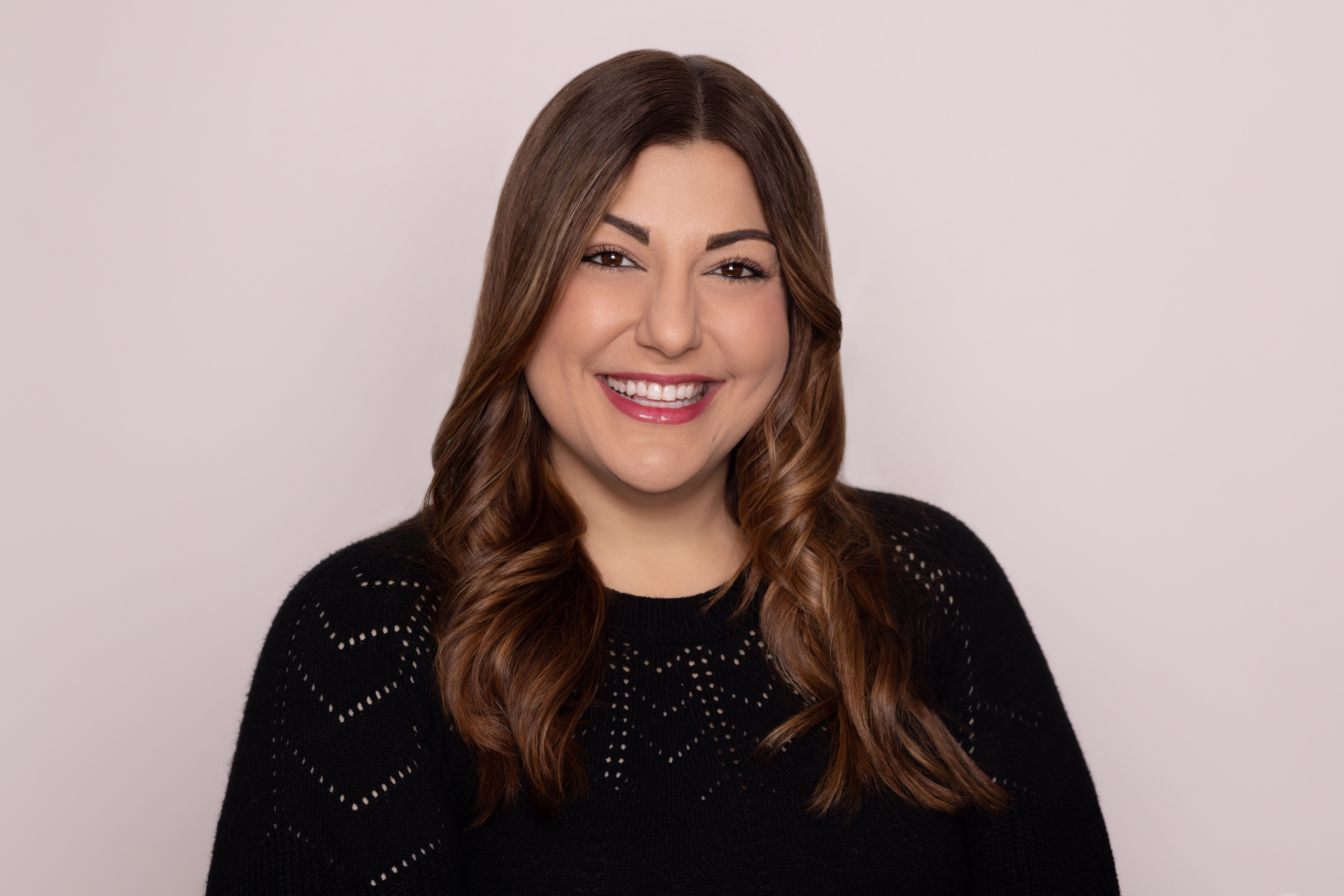 A smiling woman in a fancy black sweater.