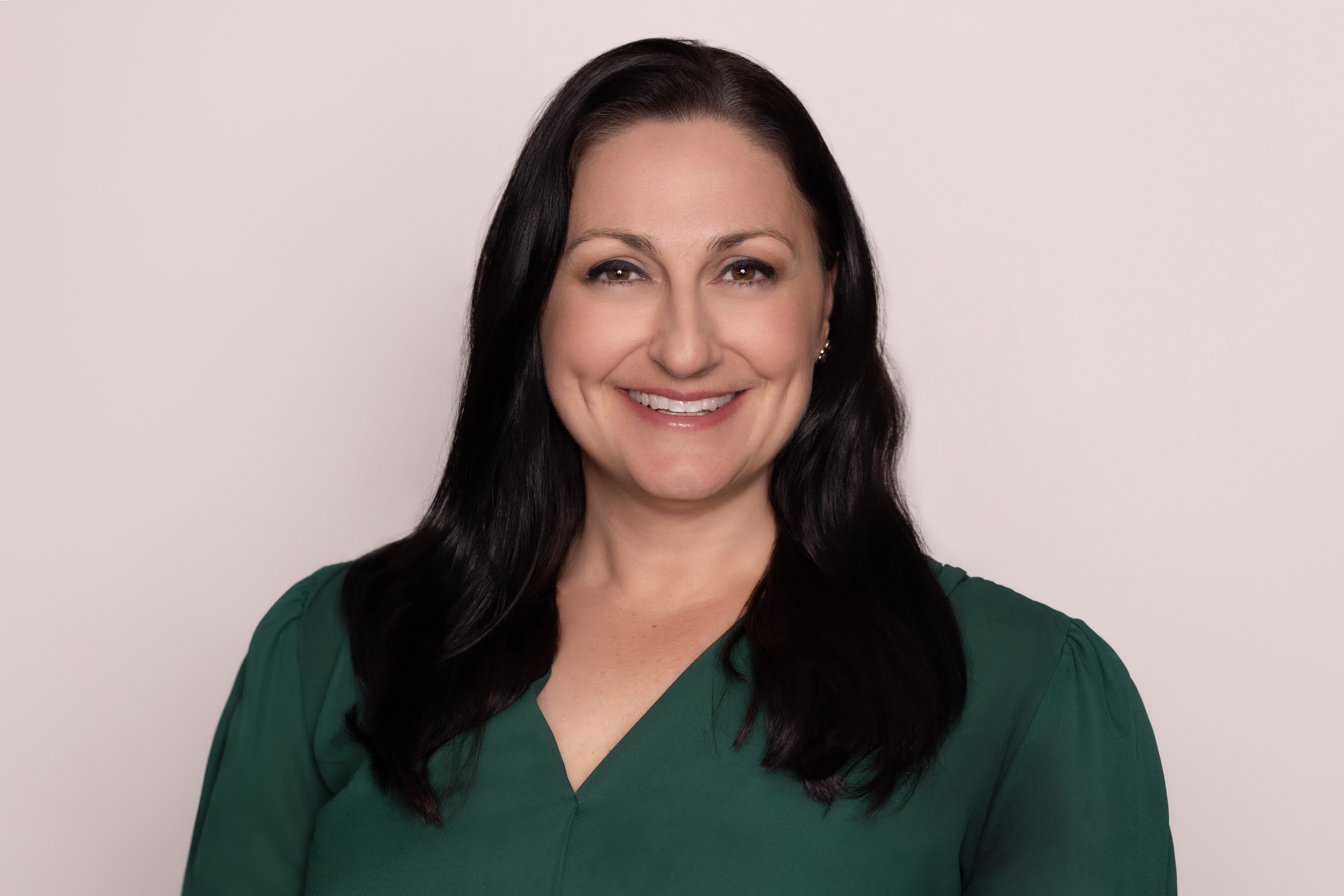 A woman smiling for the camera, wearing a green shirt.