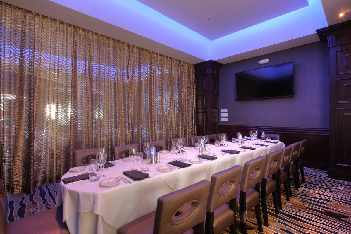 a room with a large table set with plates and wine glasses