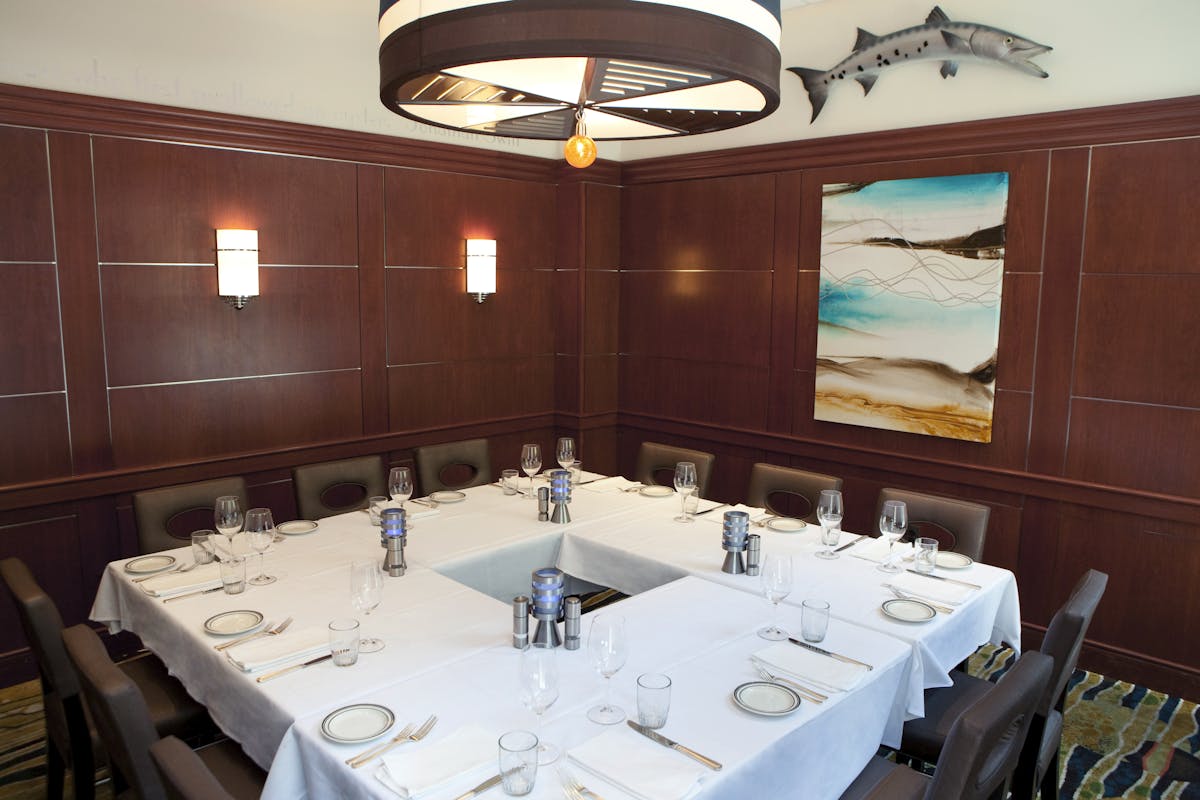 a room with a large table set with plates and wine glasses