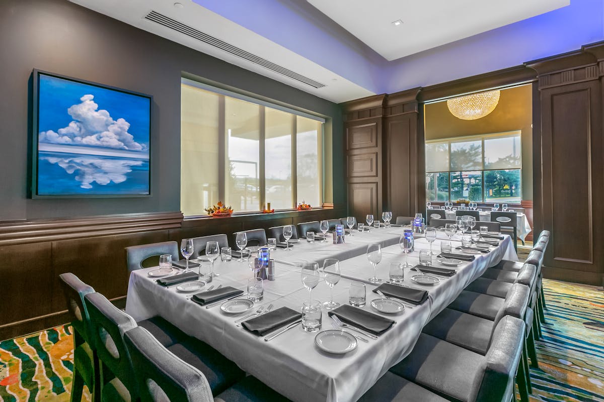 a room with a large table set with plates and wine glasses
