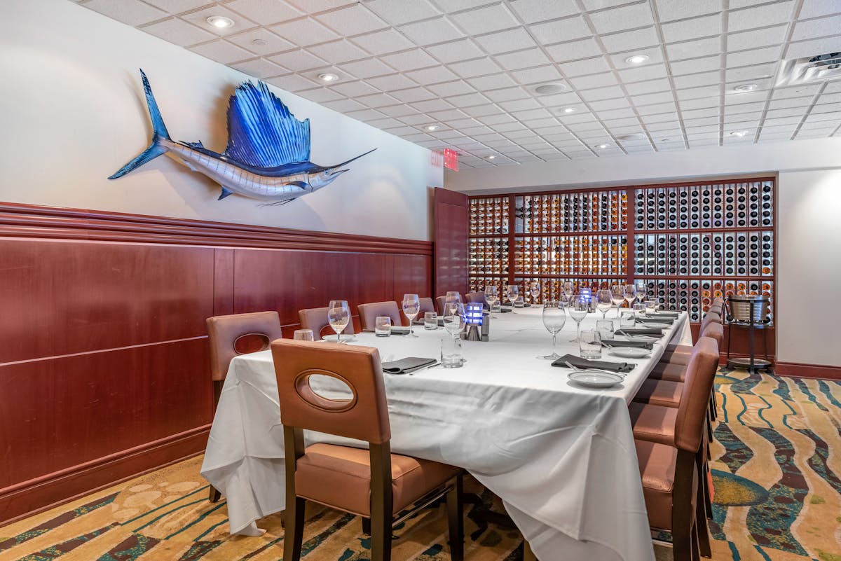 a room with a large table set with plates and wine glasses