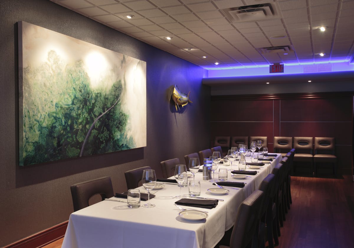 a room with a large table set with plates and wine glasses