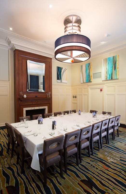 a room with a large table set with plates and wine glasses