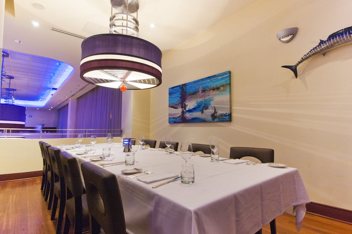 a room with a large table set with plates and wine glasses