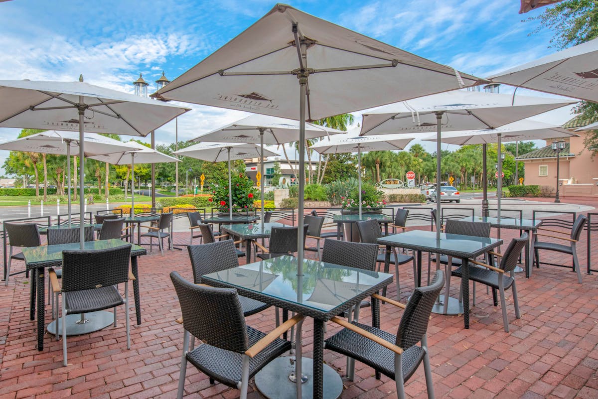 eating tables set with chairs and umbrellas outside