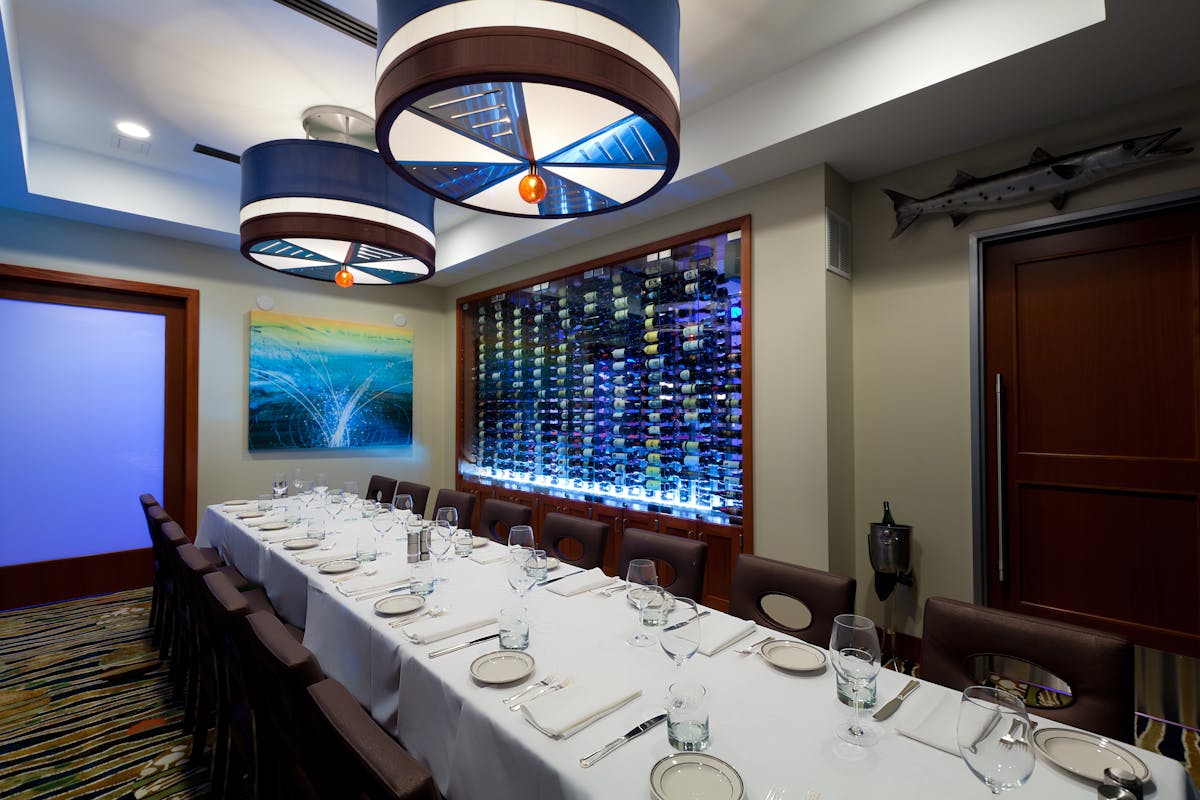 a room with a large table set with plates and wine glasses