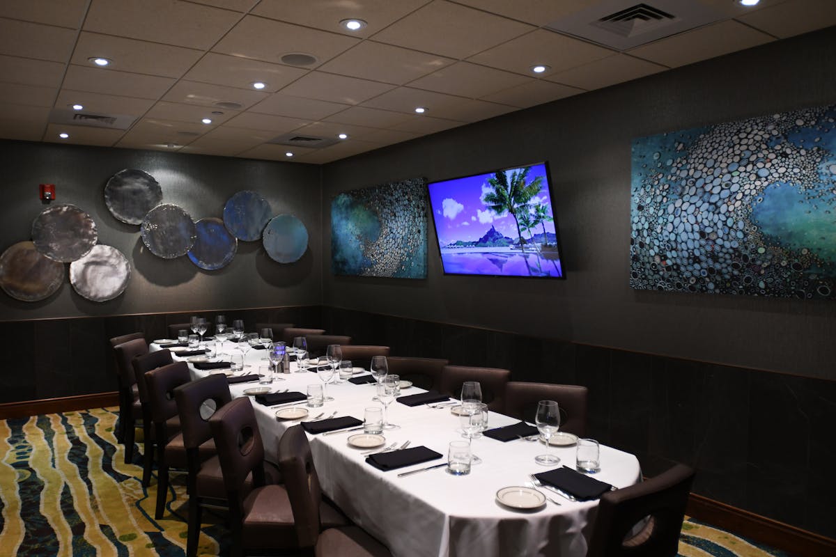 a room with a large table set with plates and wine glasses