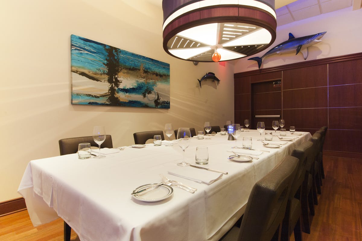 a room with a large table set with plates and wine glasses