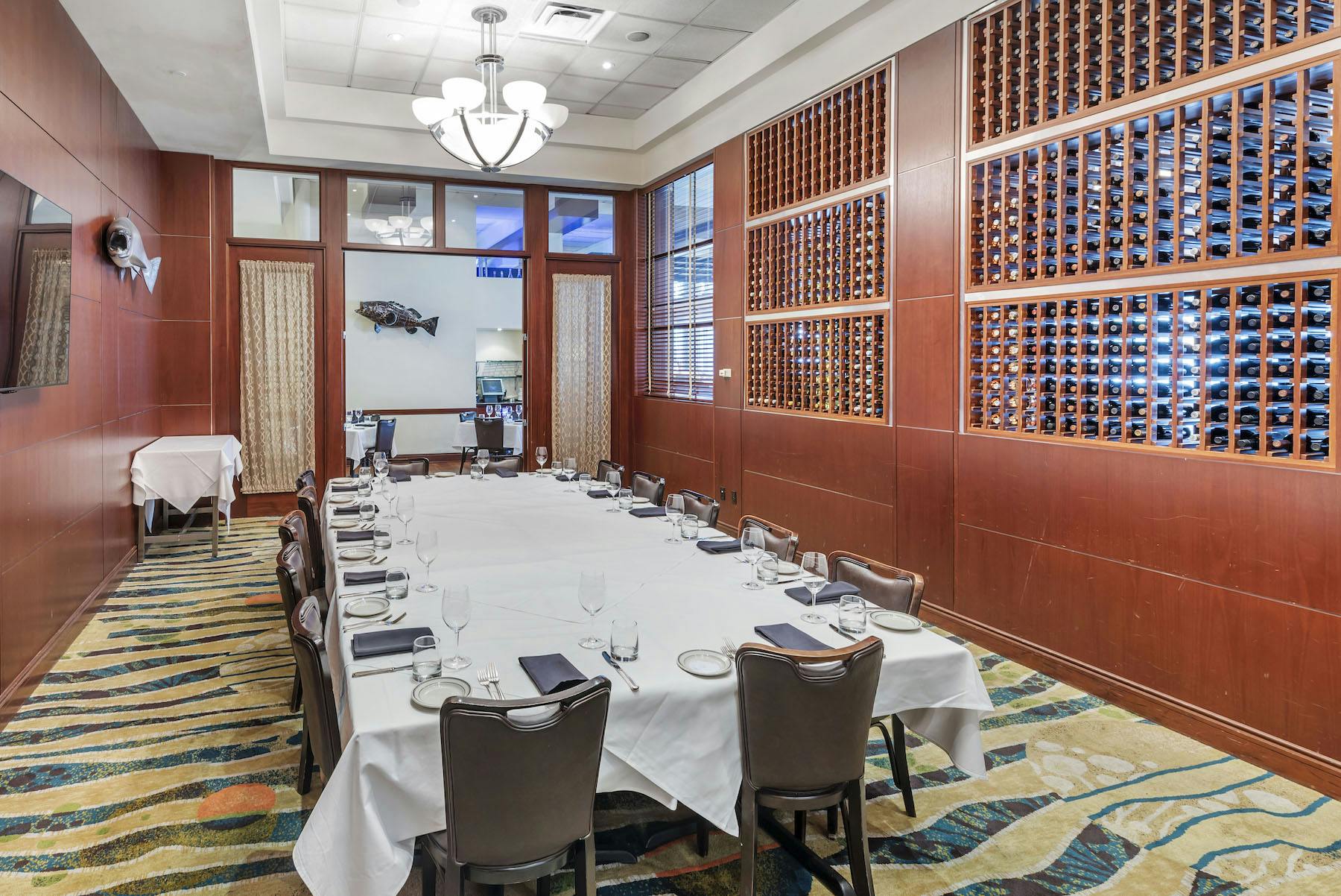 a room with a large table set with plates and wine glasses