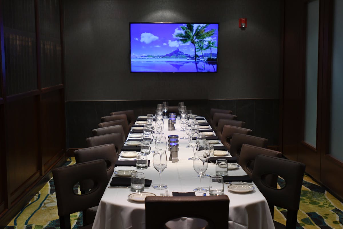 a room with a large table set with plates and wine glasses