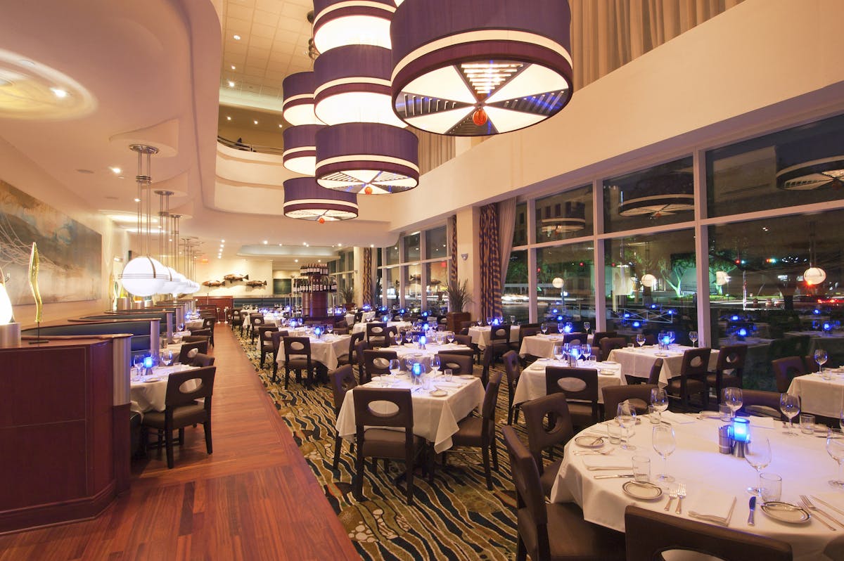 a large dining room set with tables with plates and wine glasses