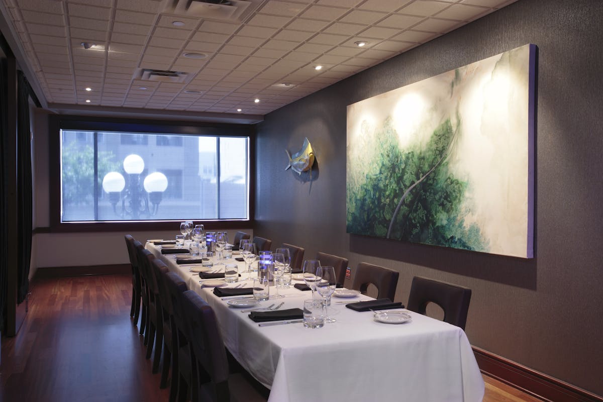 a room with a large table set with plates and wine glasses