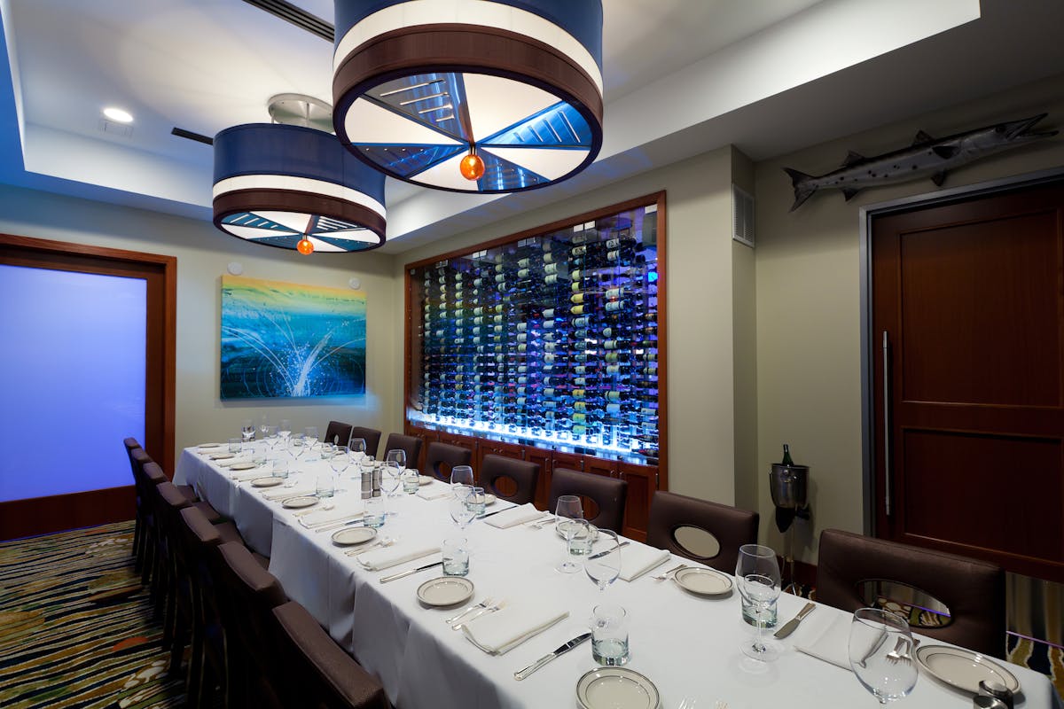 a room with a large table set with plates and wine glasses