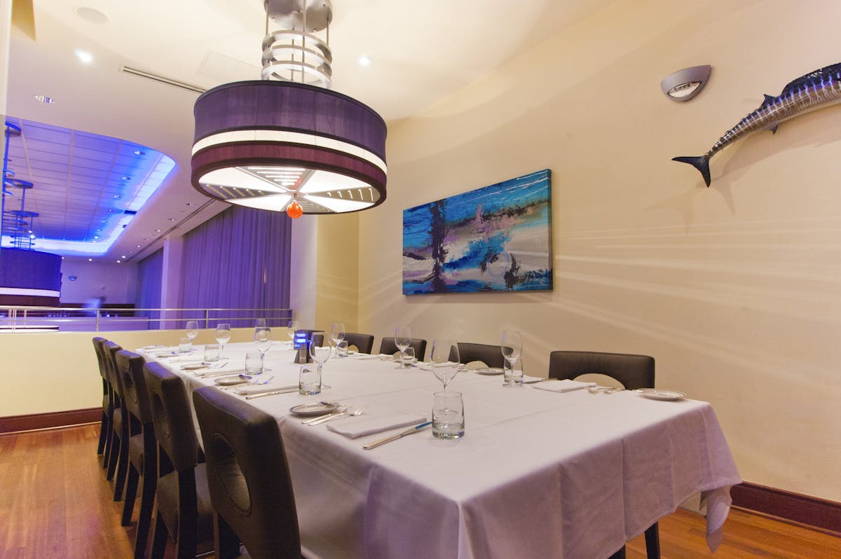 a room with a large table set with plates and wine glasses