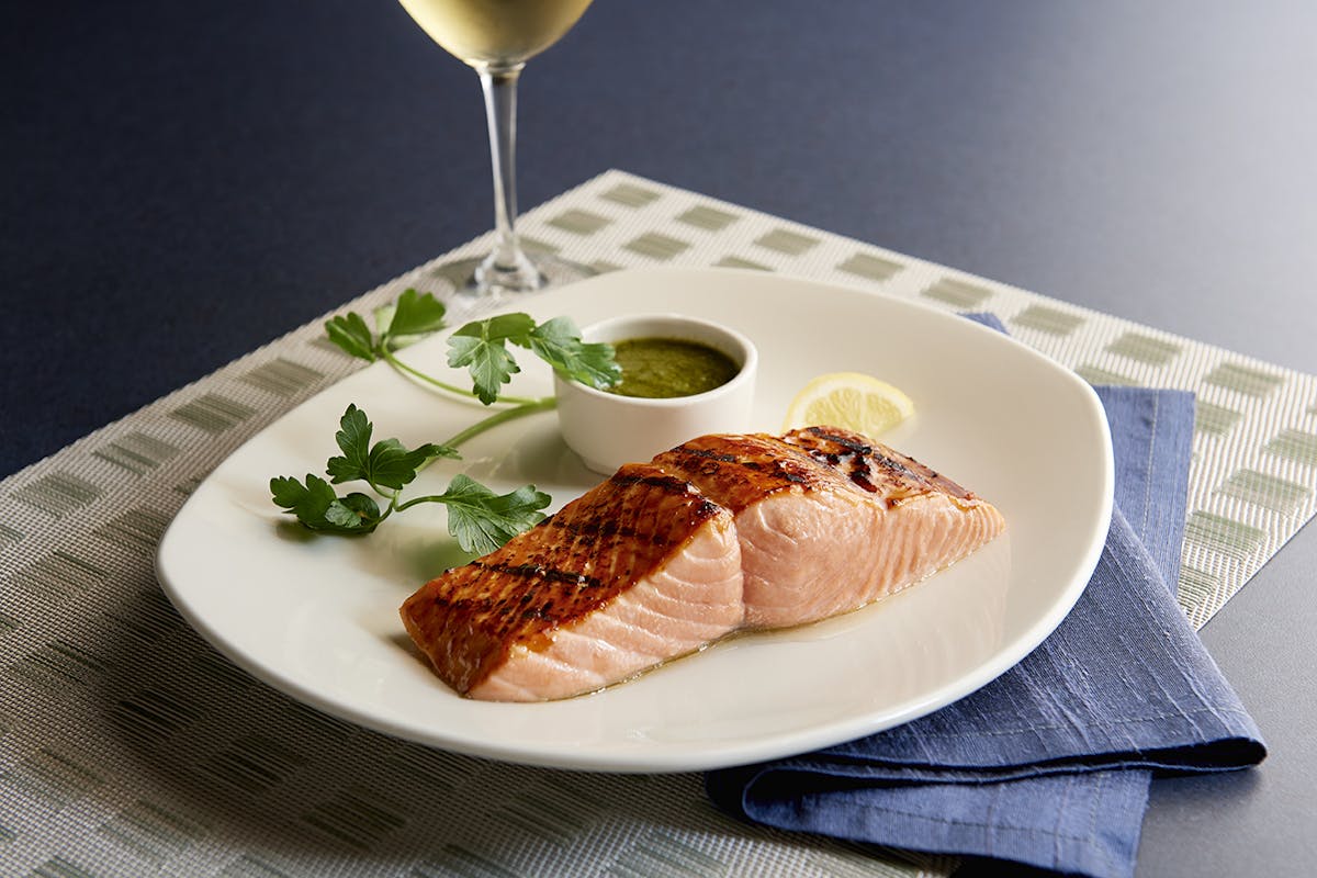 a plate of salmon with wine on a table