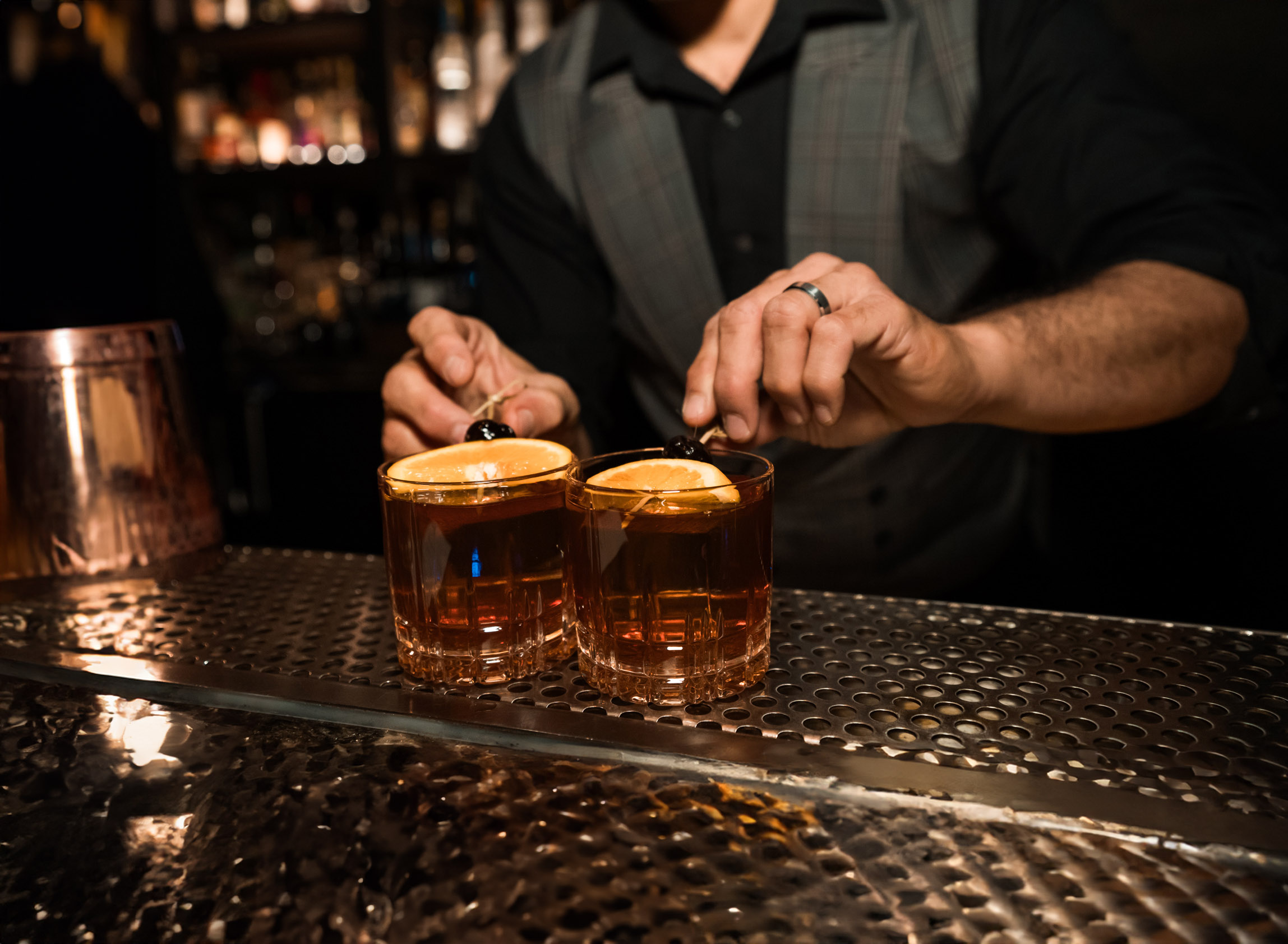 bartender topping two old fashions with cherry garnishes at Las Vegas speakeasy