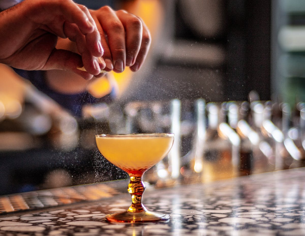 a person squeezing a lemon over a drink