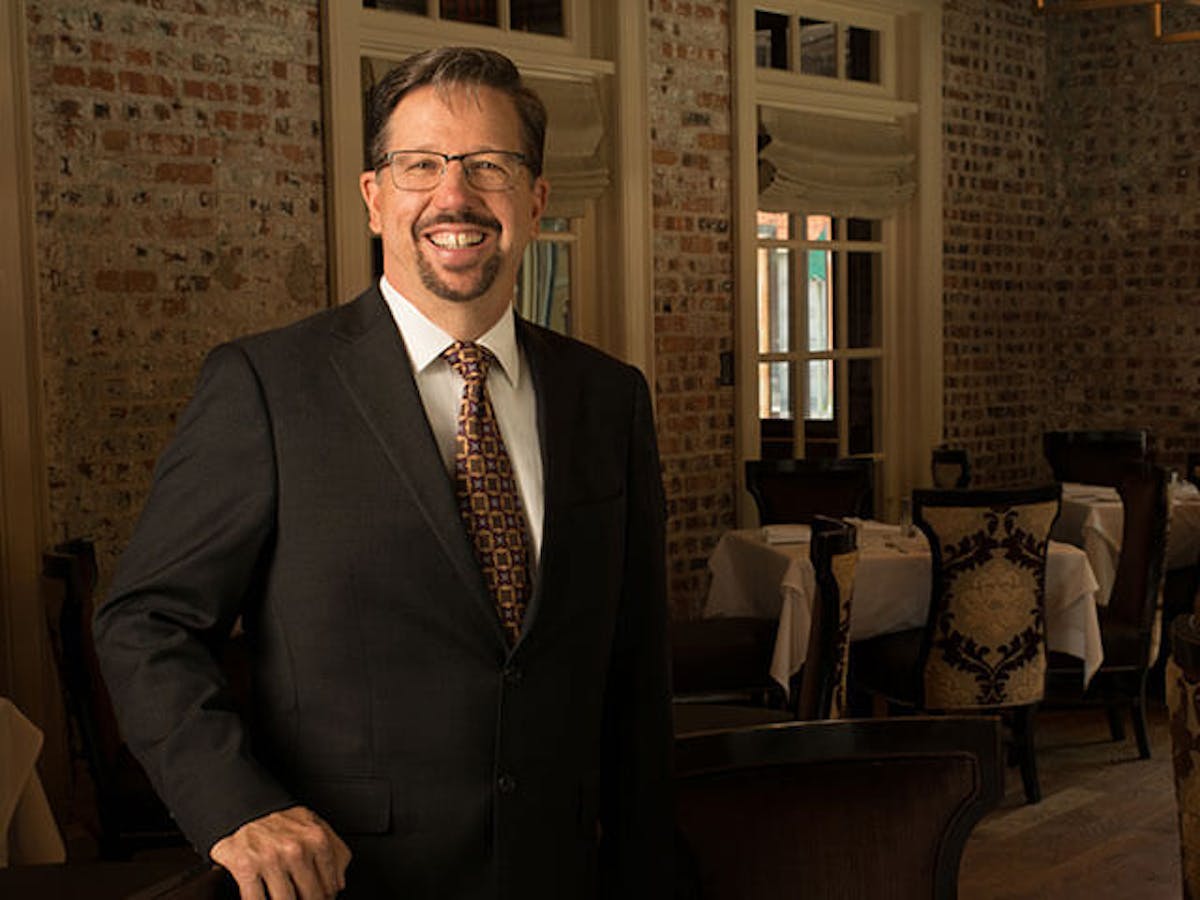 a man wearing a suit and tie standing in front of a building