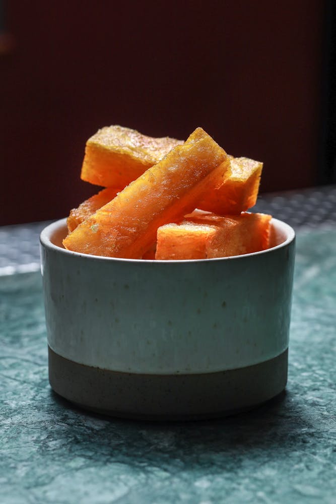 a close up of a bowl of oranges on a table