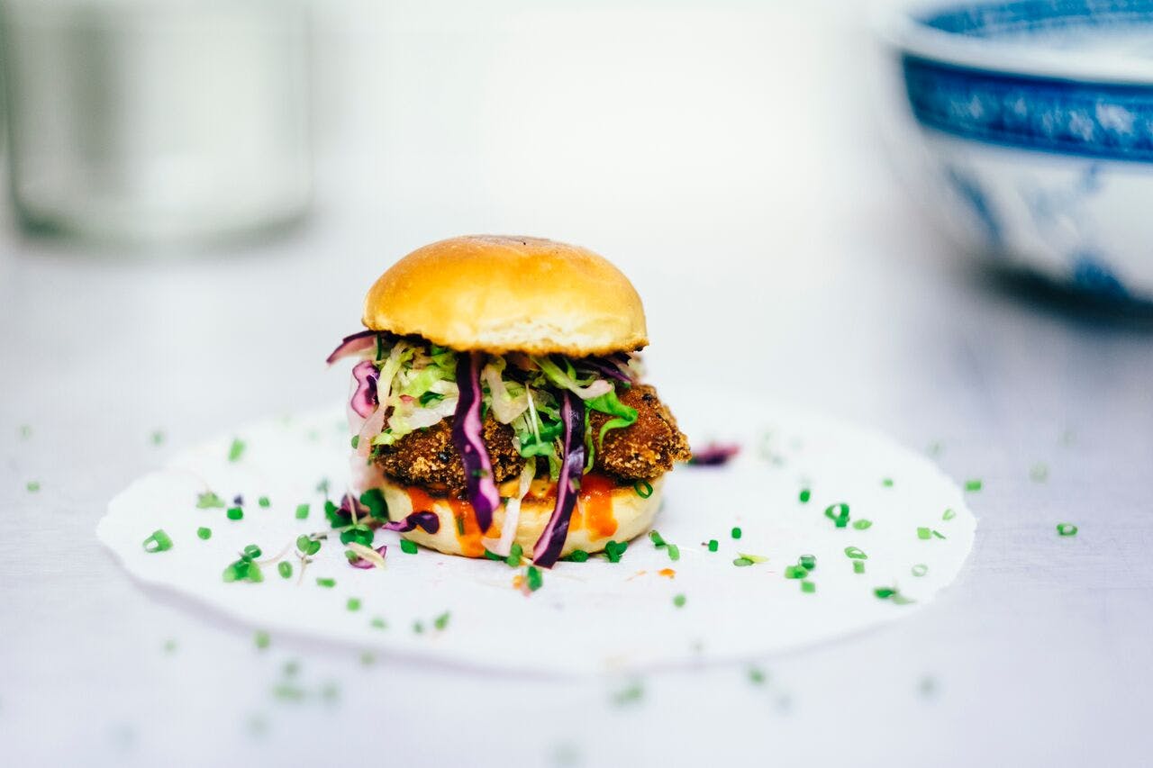 A hamburger on a white plate in a bright white background