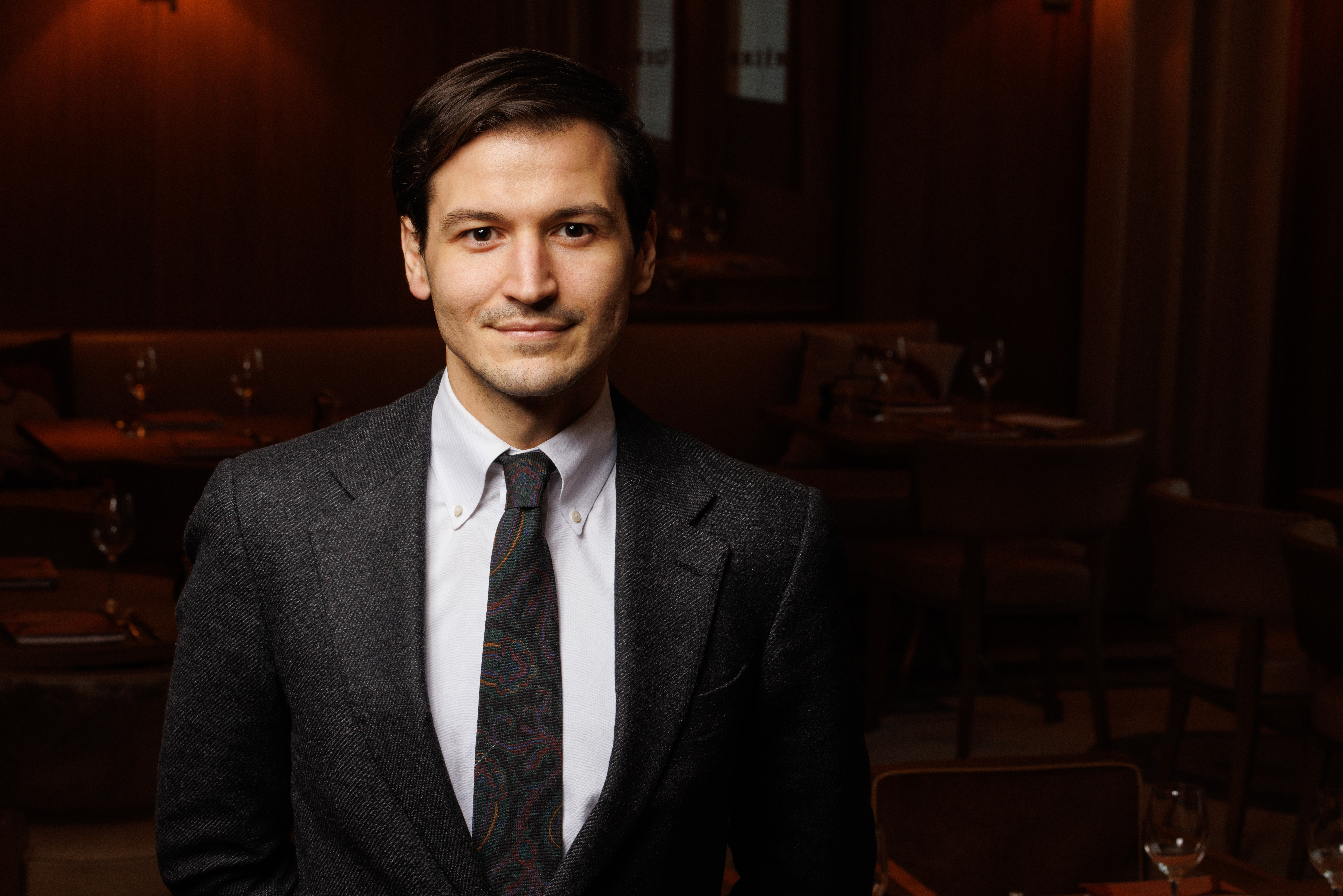 a man wearing a suit and tie smiling at the camera
