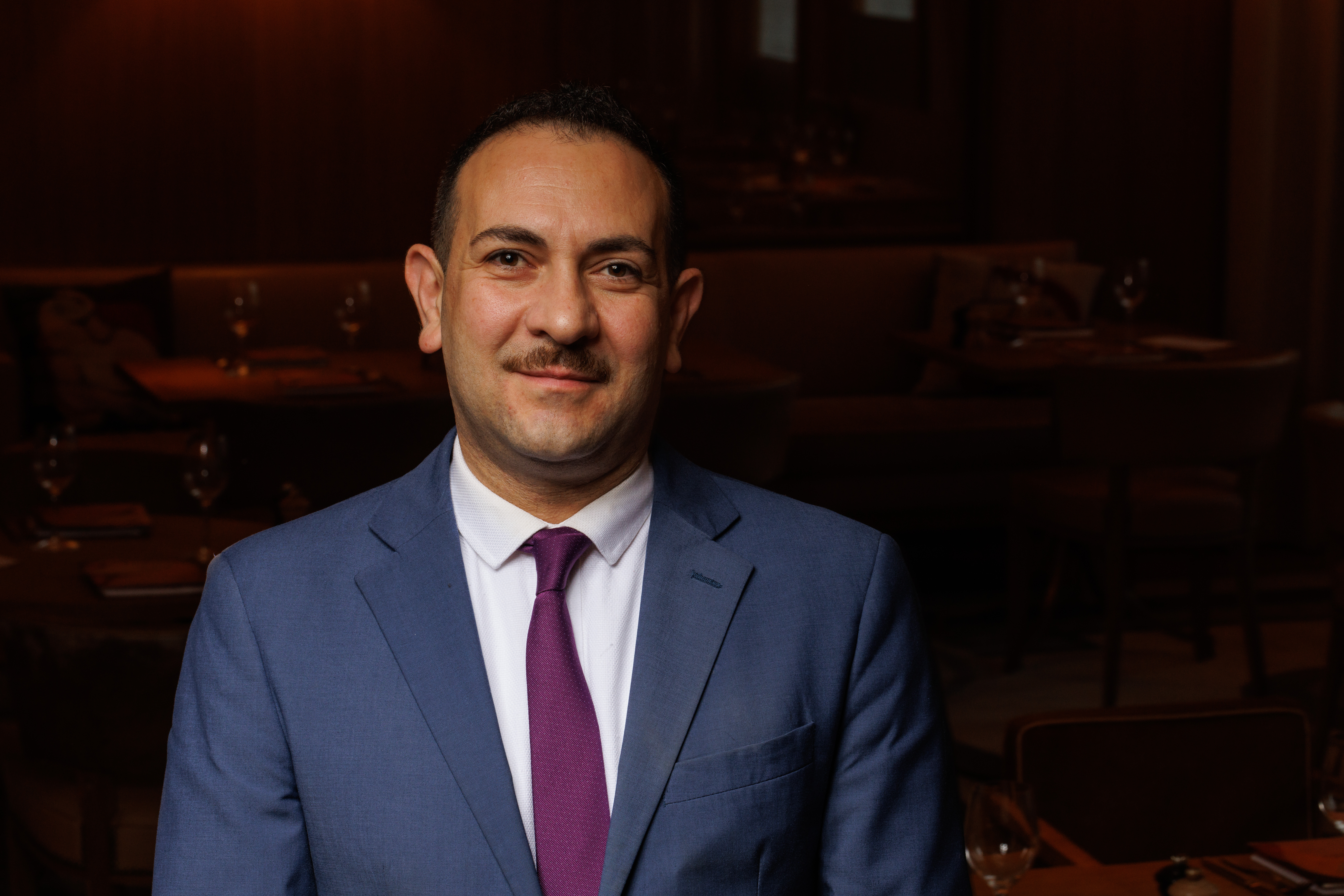 a man wearing a suit and tie smiling at the camera