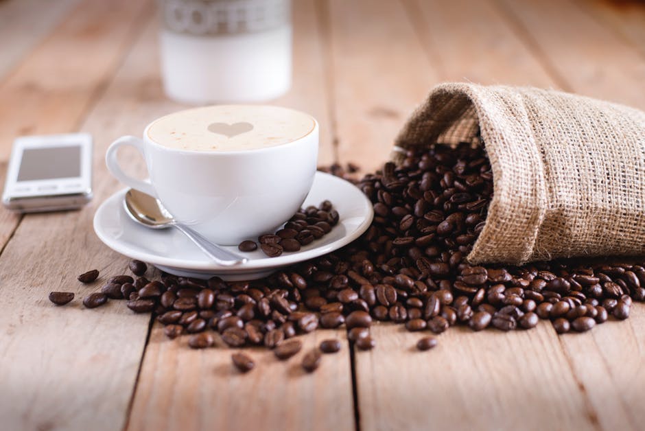 a cup of coffee sitting on top of a wooden table