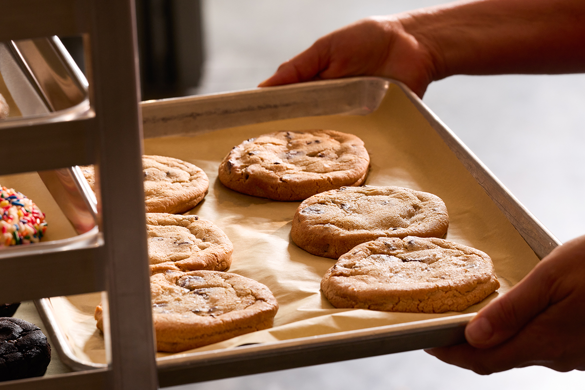 a person pulling a tray of freshly baked cookies out of a rack