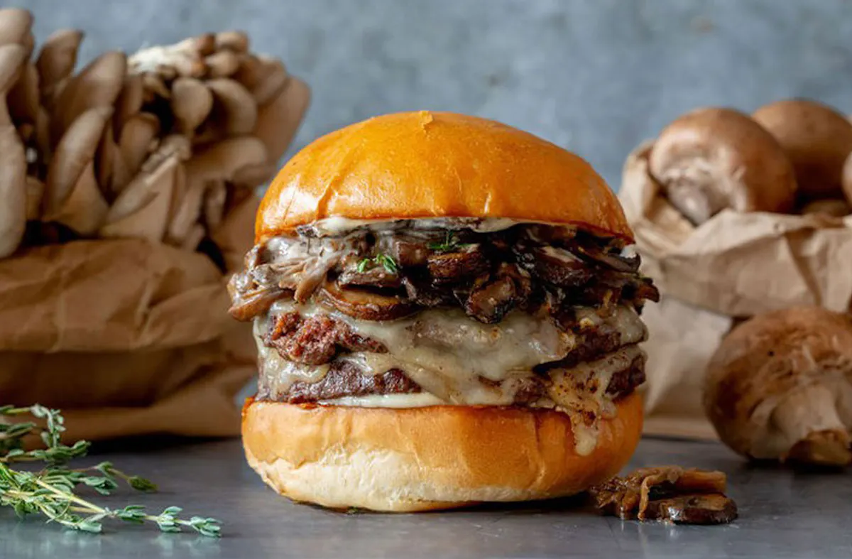 A burger with sautéed cremini and oyster mushrooms with swiss cheese and garlic mayo.