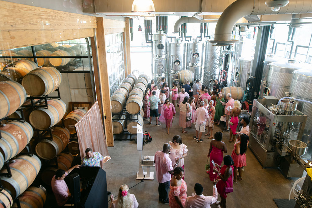 a group of people dressed in pink enjoying a party in a winery