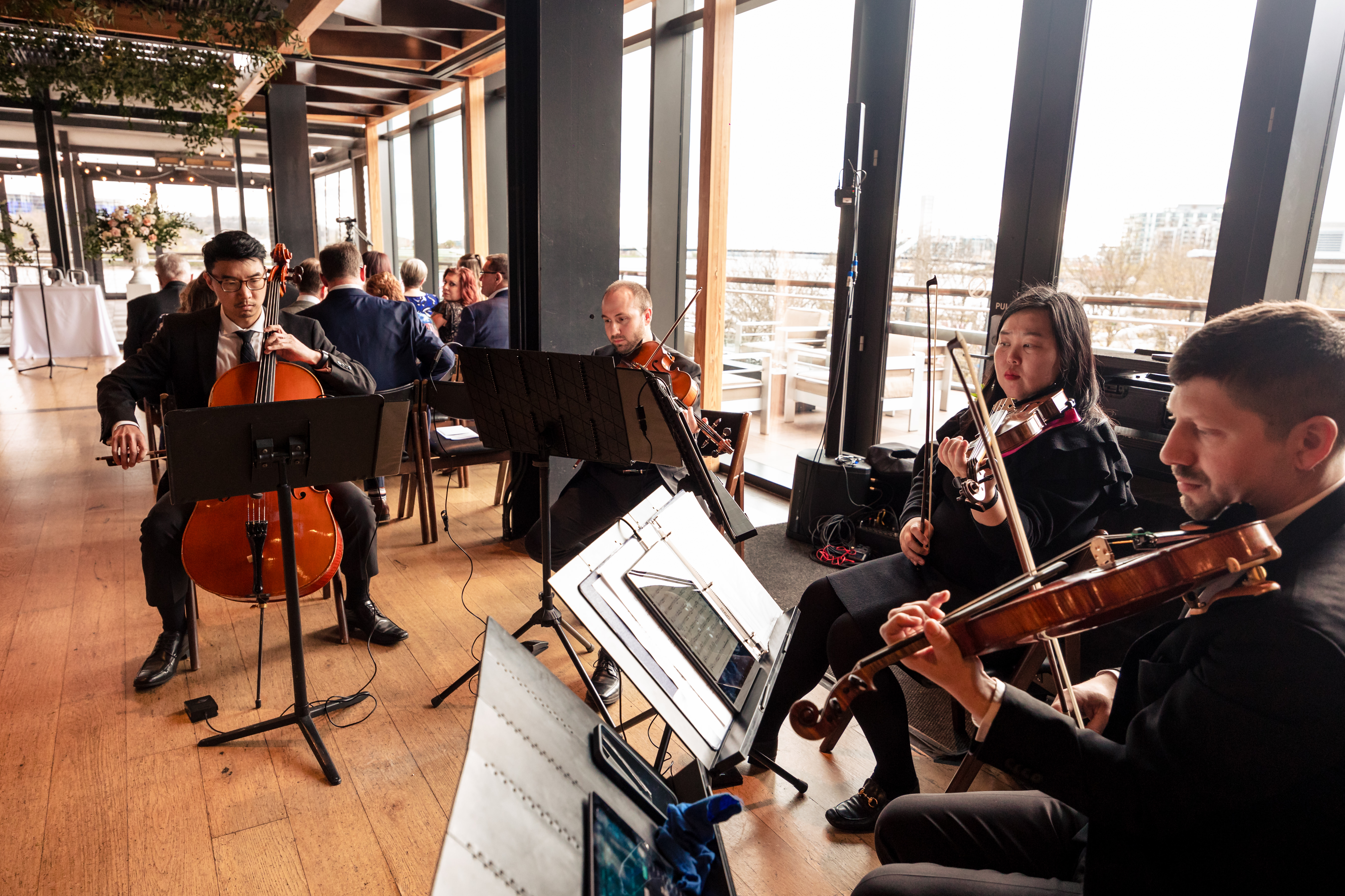 a string orchestra plays during a wedding reception on district winery's rooftop
