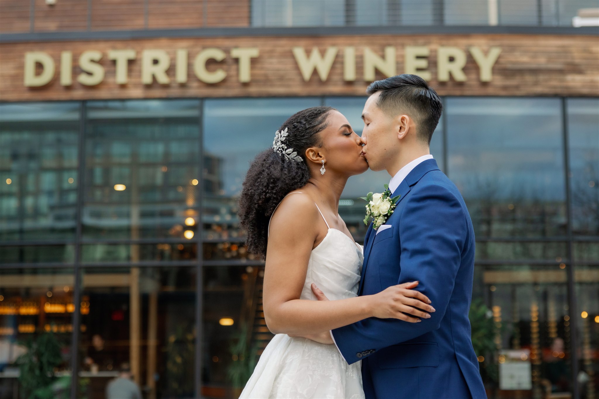 a bride and groom exchange a kiss  in front of District Winery