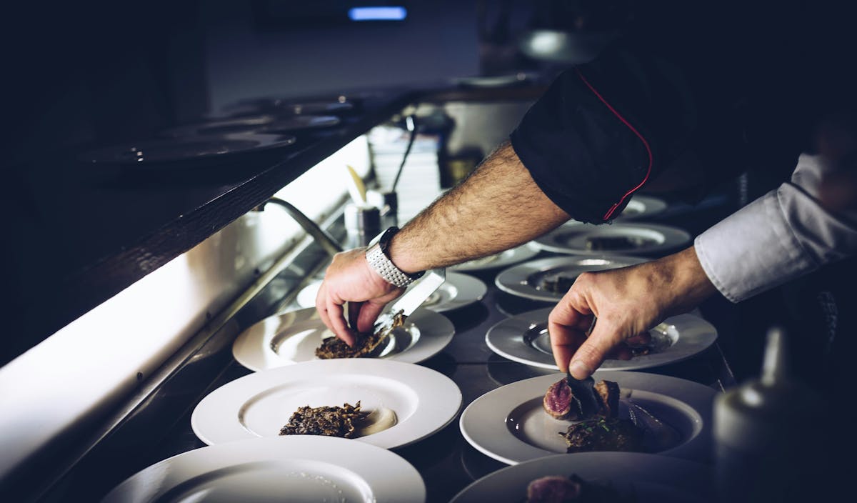 man's hands placing food on plates